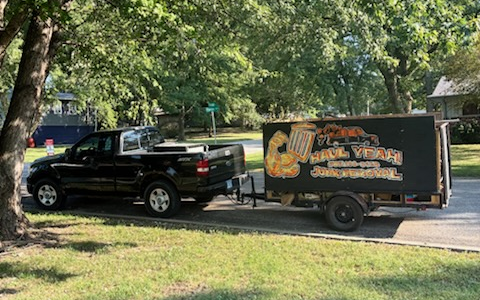 Cody and a team member standing on opposite sides of trailer full of junk in Hiawatha, KS and Surrounding Areas giving a thumbs up and peace sign respectively